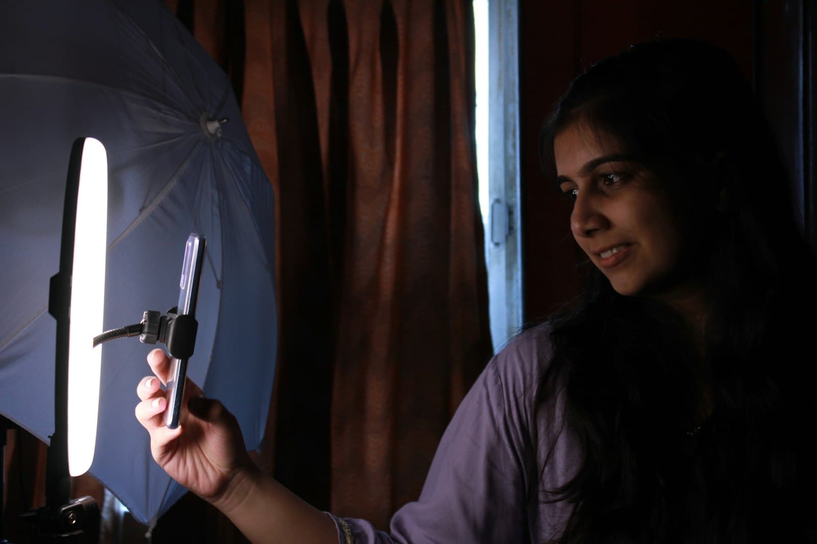 A woman holding a cell phone in front of a light